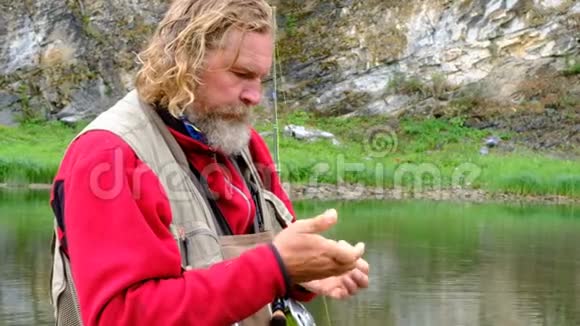 渔夫把苍蝇拴在钩子上去钓鱼老人的手特写运动和爱好视频的预览图