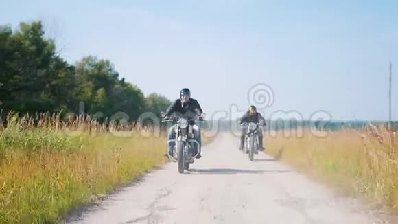 两个骑摩托车的人骑着摩托车在黑场上尘土飞扬的道路上视频的预览图