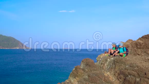 男孩们坐在地中海沿岸的一块岩石上视频的预览图