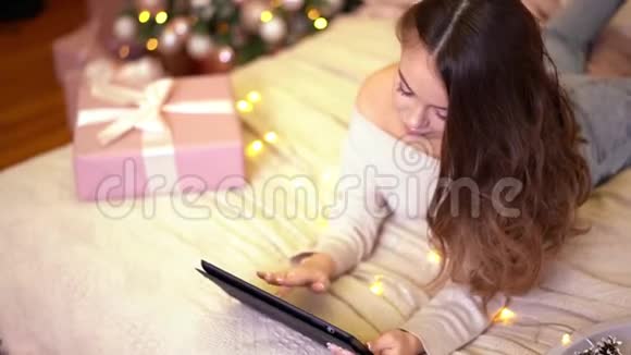 年轻漂亮的女人在圣诞节或新年用平板电脑祝贺她的亲戚朋友视频的预览图