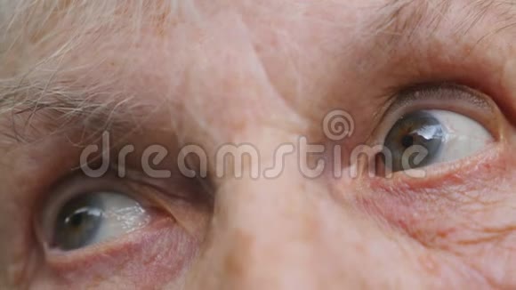 老妇人看着疲惫的视线离开了一位有皱纹的老太太的眼睛特写悲伤的肖像视频的预览图