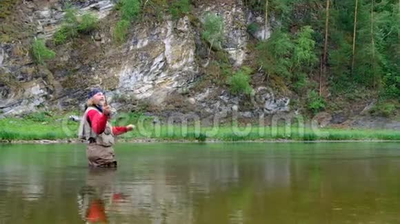 一位留着长发和圣诞老人胡须的老人站在水里拿着一根钓鱼竿钓鱼视频的预览图