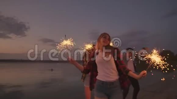 跳舞的朋友带着烟火玩得开心在海滩上一起庆祝夏天的节日视频的预览图