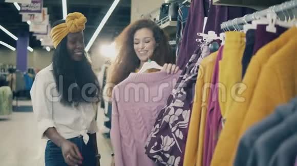 微笑的女士们在购物时挑选衣服视频的预览图