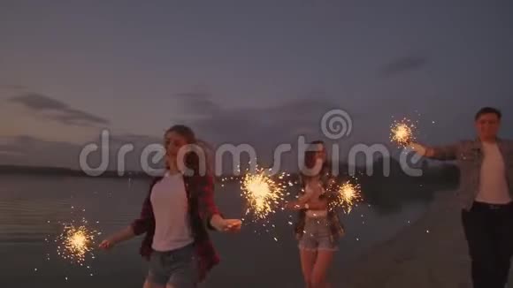 一群男男女女的朋友在海滩上快乐地奔跑着用火花和烟花庆祝节日视频的预览图