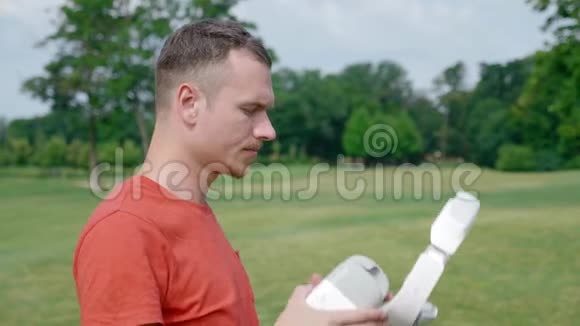 一个男人在公园里把一个虚拟现实耳机放在头上开始使用然后把它摘下视频的预览图