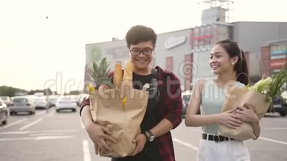 可爱的快乐越南夫妇手里拿着超市附近的大食品袋视频的预览图