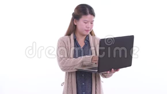 快乐的年轻亚洲女人一边说话一边用笔记本电脑准备过冬视频的预览图