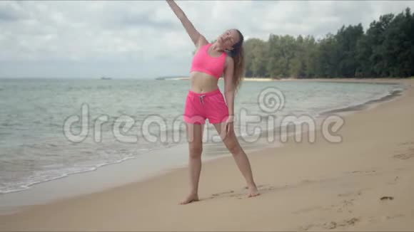 穿着粉色泳衣在沙滩上健身的活跃女性视频的预览图