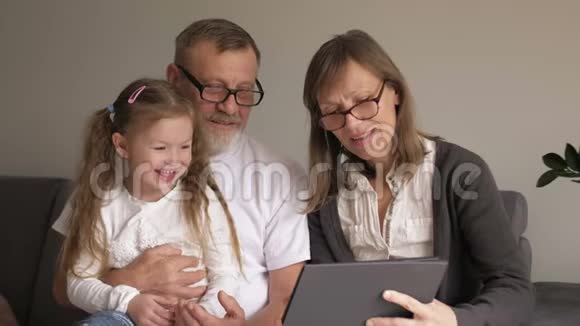 家庭世代科技和人的概念微笑的祖父孙女和带平板电脑的祖母视频的预览图