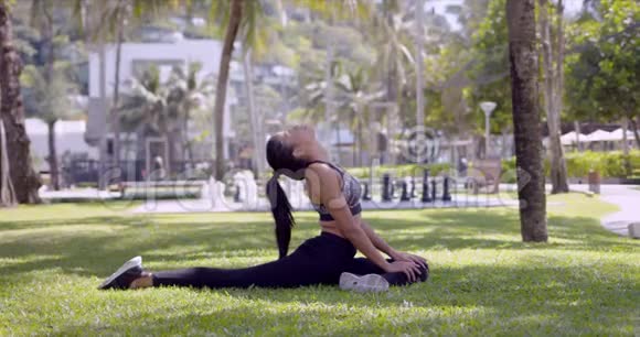 亚洲苗条的女人伸着脖子和腿坐在公园里视频的预览图