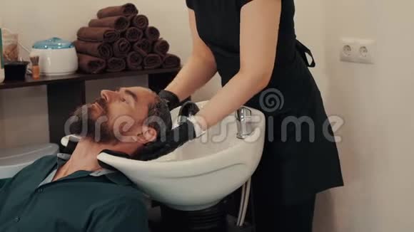 发型师在理发店洗手男性头发在理发店用按摩把洗头关起来男理发师视频的预览图