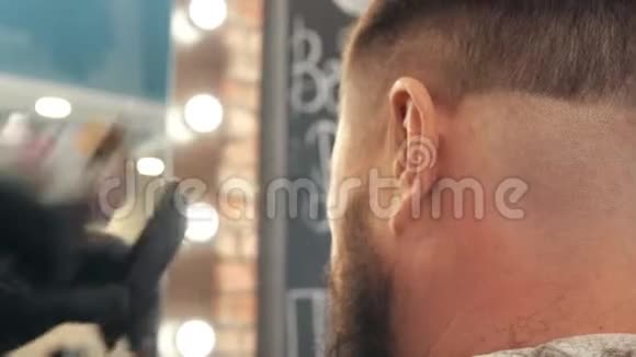 理发师在理发店里用理发机理发和梳头将男性发型与电动剃须刀合拢视频的预览图