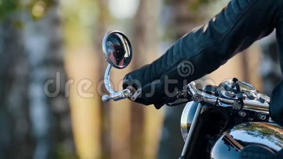 一个残暴的摩托车手坐在摩托车上看着后视镜视频的预览图