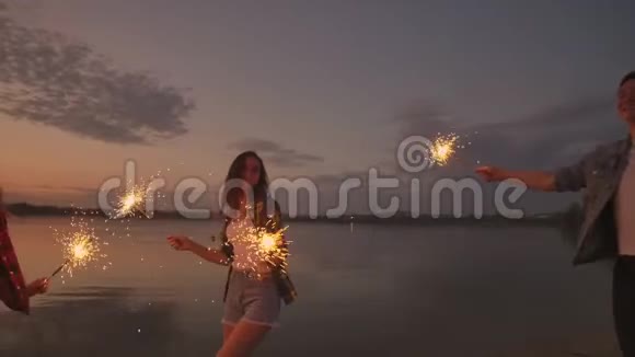 跳舞的朋友带着烟火玩得开心在海滩上一起庆祝夏天的节日视频的预览图