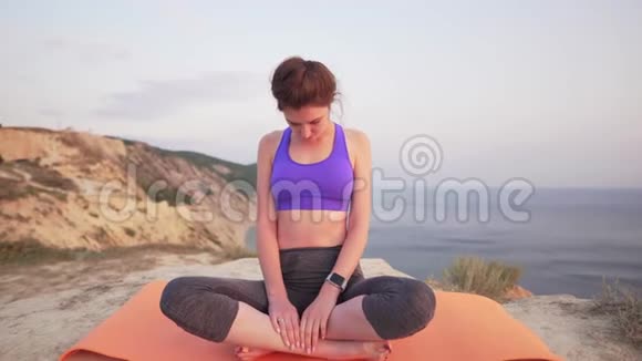 运动女孩练习瑜伽专注于呼吸努力让自己平静下来背景是山和海刮风视频的预览图