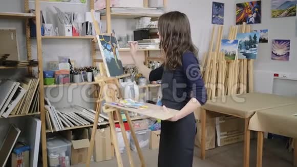学生艺术家女孩拿着颜料调色板站在画架附近视频的预览图
