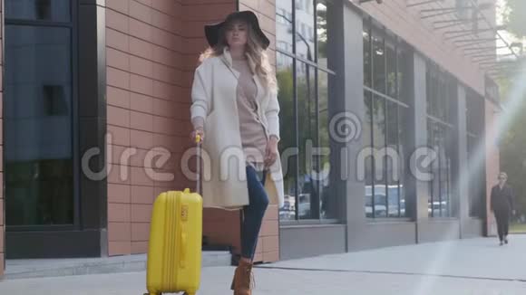 一位戴着帽子和外套的漂亮女士站在酒店附近视频的预览图