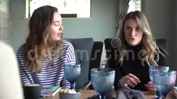 快乐的女性朋友在咖啡馆聊天两个美丽的年轻女人闲聊和喝咖啡友谊概念视频的预览图