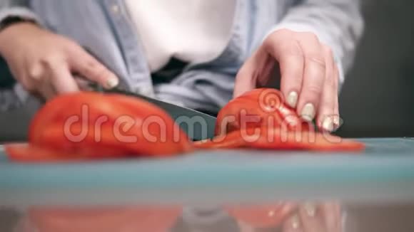 女性的手在切割板上缓慢地切割新鲜的红色番茄把女人的手紧紧视频的预览图