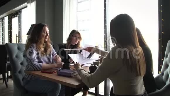 一群四个年轻的女商人聚集在一张桌子旁在咖啡馆里讨论一个有趣的想法视频的预览图