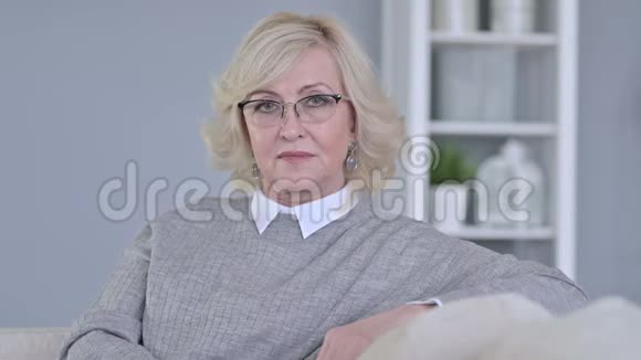 沙发上镜头微笑的老女人的肖像视频的预览图
