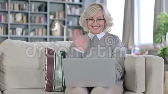坐在沙发上用笔记本电脑做视频聊天的老女人视频的预览图