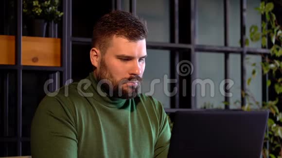 留胡子的商人坐在酒吧里手提电脑和一杯咖啡自由职业者福利视频的预览图