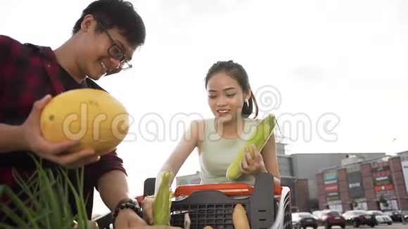 可爱开朗的亚洲夫妇把从购物车买来的食物放进包里视频的预览图