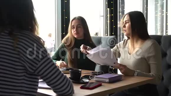 四个年轻探员坐在咖啡馆里讨论文件和组织工作视频的预览图