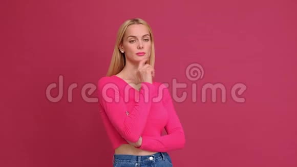 漂亮的年轻女子金发穿着红色T恤和牛仔裤摆在粉红色的背景上表现出不同的情绪惊喜视频的预览图