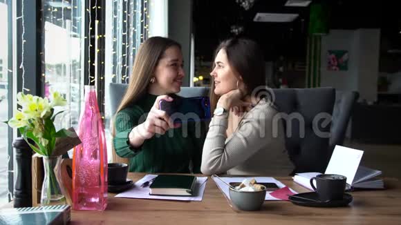快乐的两个女人在镜头前微笑和摆姿势用现代手机拍照视频的预览图