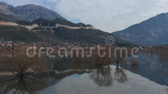 飞越希腊被洪水淹没的山谷被淹没的田野道路背景上的群山有人居住的定居点视频的预览图