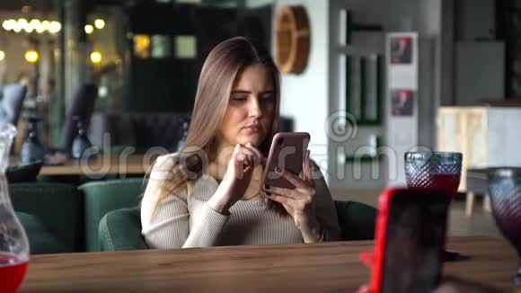 女孩坐在咖啡店里在度假时间为社交媒体玩手机视频的预览图