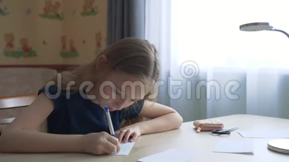 十几岁的女孩在窗口背景的桌子上用钢笔写字小女孩用笔在格子上写字视频的预览图