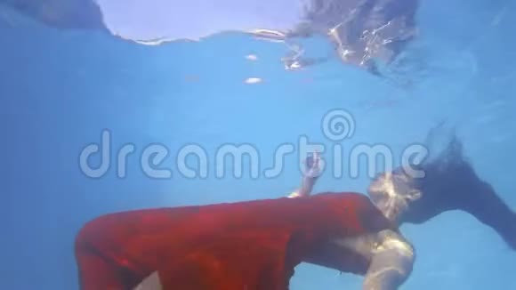 水下拍摄的一名穿红色衣服的年轻女子在水面附近游泳视频的预览图