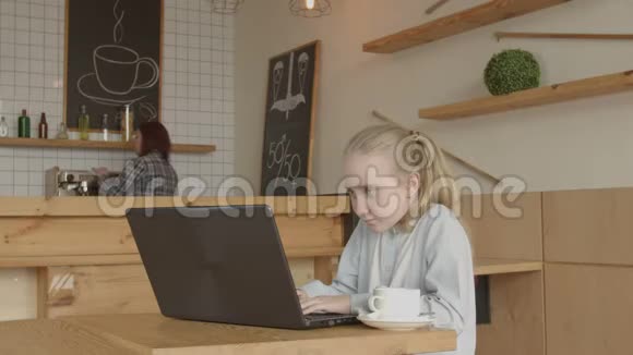 小女孩坐在咖啡桌上用笔记本电脑视频的预览图