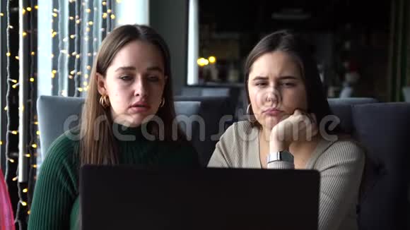 两个年轻的女商人坐在一张桌子旁手提电脑的咖啡馆里视频的预览图