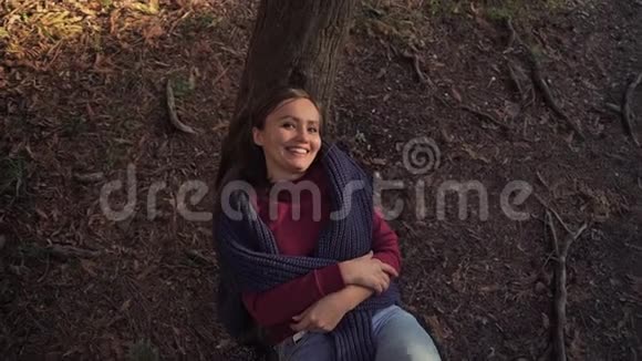 美丽的女孩躺在树干上可爱的微笑俯视视频的预览图