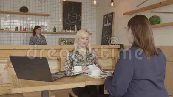 女商人在咖啡馆里握手交易视频的预览图
