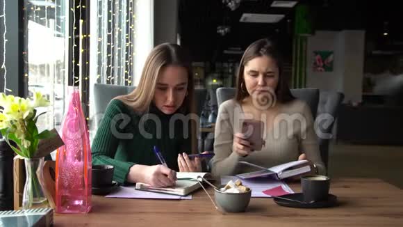 两个年轻的女商人坐在咖啡馆里打电话视频的预览图