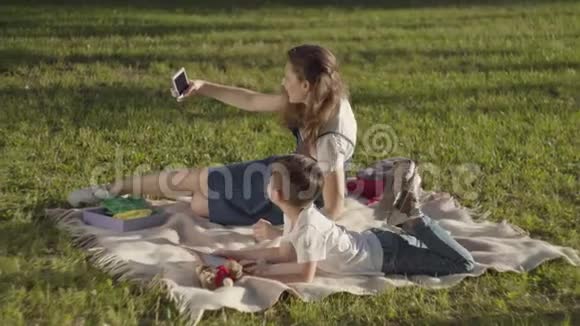姐姐和弟弟一起在户外玩男孩在看书女孩在公园自拍视频的预览图