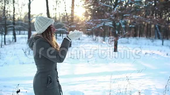 在冬天的森林里吹雪女人在户外玩得很开心季节性活动女孩笑着穿暖衣服视频的预览图