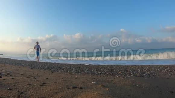 摄影师在黎明时漫步在海滩上视频的预览图