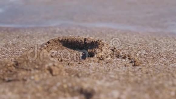 轻波在沙滩特写镜头中洗去脚印视频的预览图