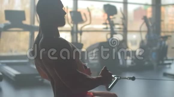 一个疲惫的运动男子坐在健身房的室内划船器上人和健身观念视频的预览图