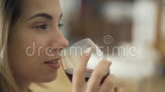 近脸的成年白种人女人从酒杯里喝红酒在家里或家里喝酒的女士视频的预览图