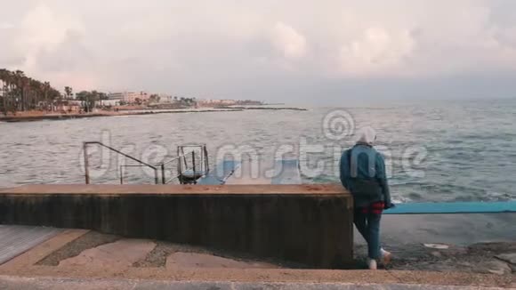 孤独悲伤的女孩看着大海站在码头的孤独的年轻女人孤独的女孩在恶劣的天气散步少女视频的预览图