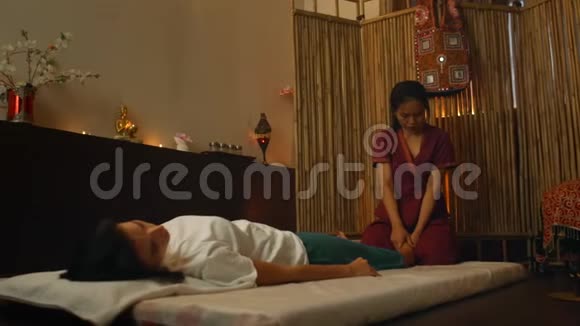 亚洲人用泰国的民族服装做按摩欧洲的亚洲水疗沙龙年轻的白种人女性放松视频的预览图