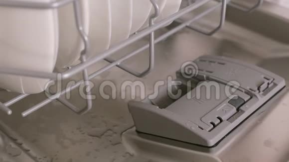 女人手在洗碗机的自动隔间里放洗衣片视频的预览图